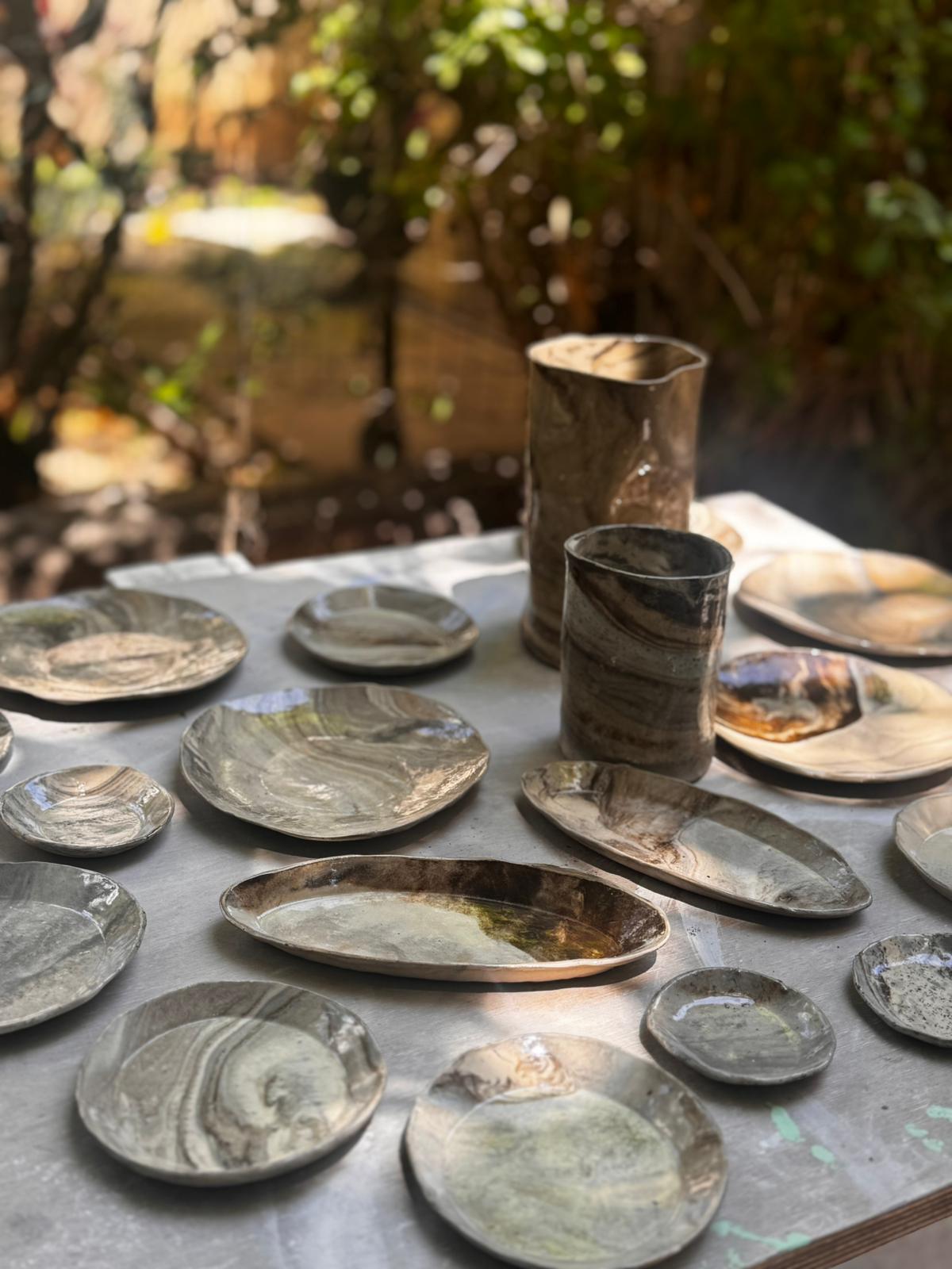 שולחן בגינה ועליו צלחות וכדים בטכניקת מרבלינג