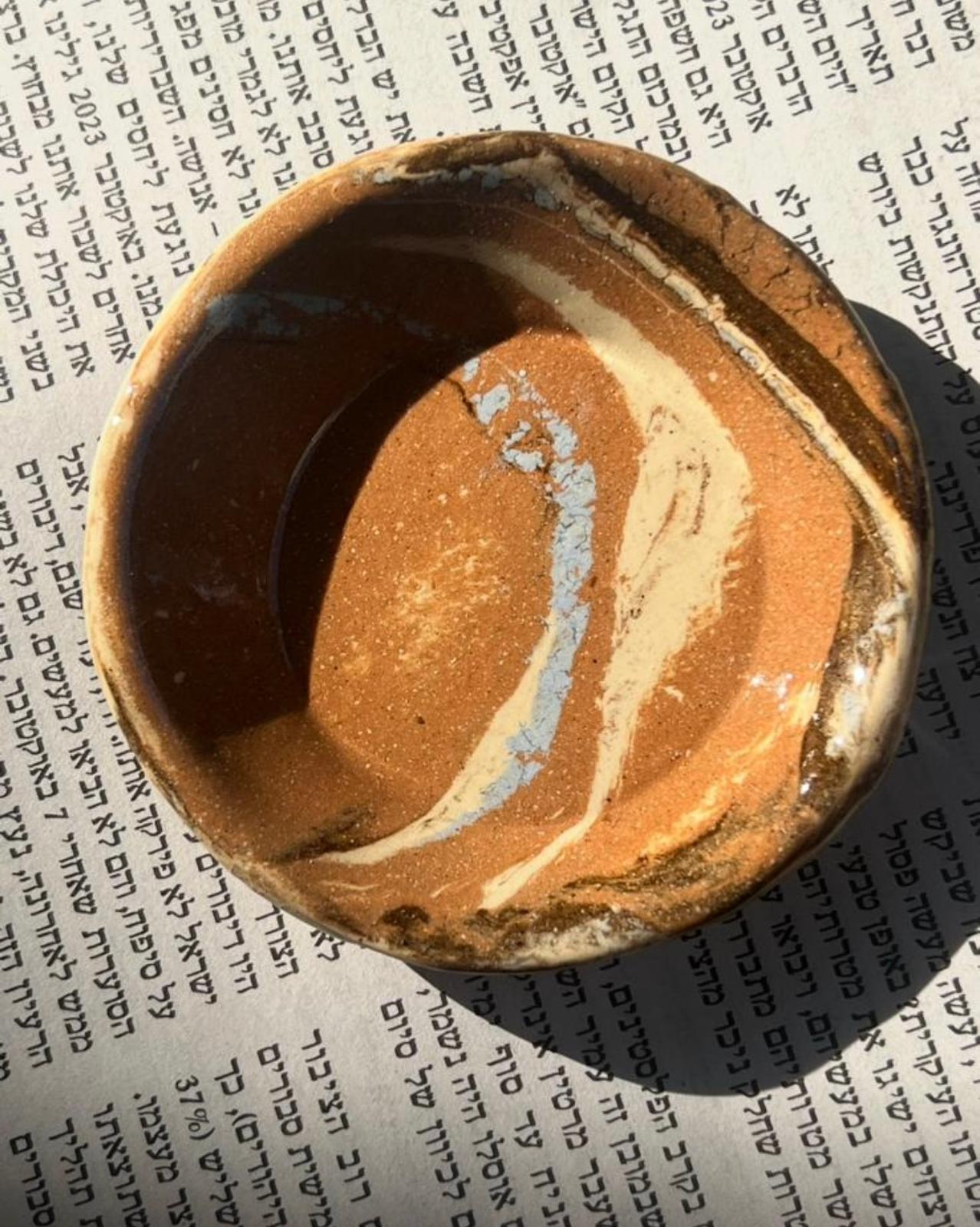 קערה משוישת מונחת על דף טקסט בעברית